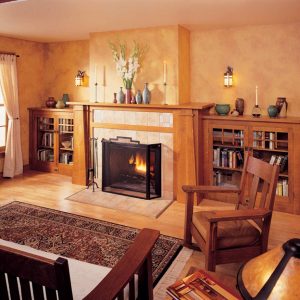 Interior of a 1990s-style home in shades of taupe, with dark wood furniture and a fireplace flanked by bookcases.