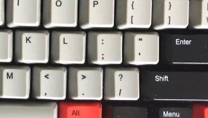 A close-up of a computer keyboard with keys in gray, black, and red.