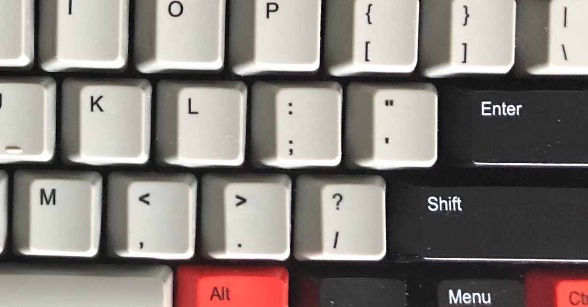 A close-up of a computer keyboard with keys in gray, black, and red.