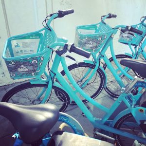 Side view of several bright blue ride share bikes standing next to each other.