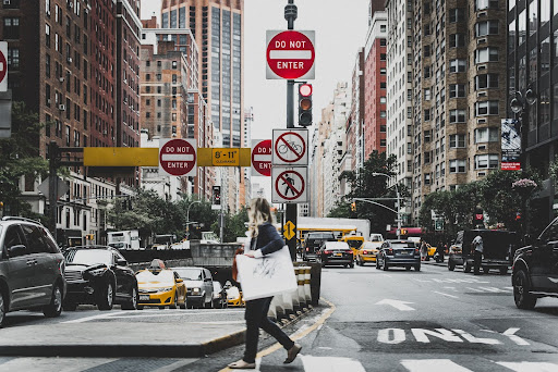 A person holding a large bad walks along a city street.