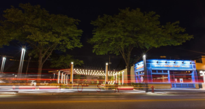 The Wauwatosa, WI 69th Street Pedestrian Plaza park and Rocket Baby Bakery with blurred effect of cars driving past.