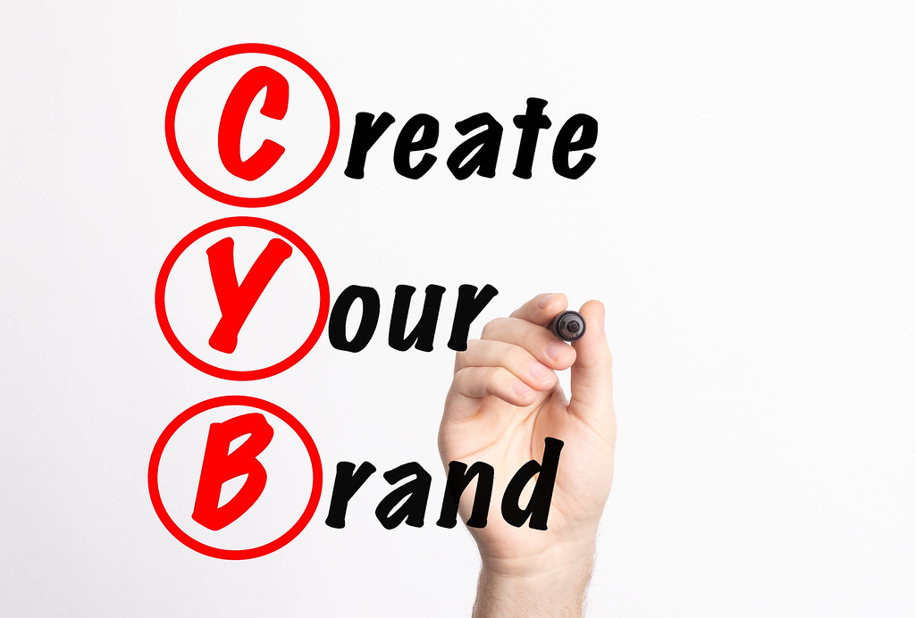 Hand holding up a marker with words "Create Your Brand."