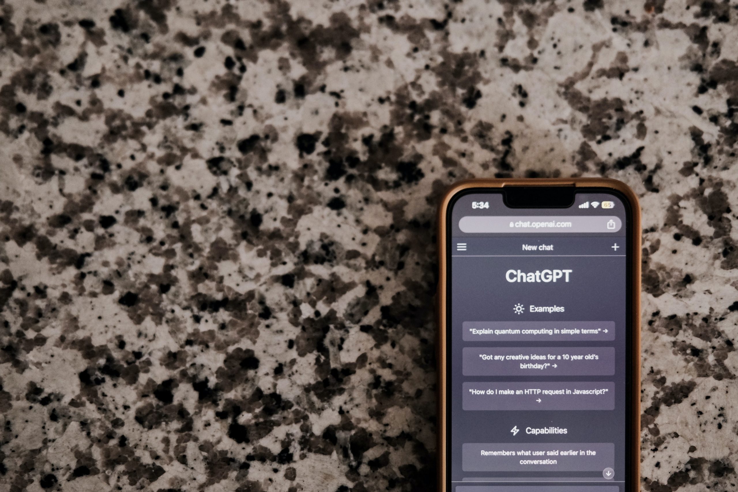 An iPhone sitting on a granite countertop. The phone's screen displays ChatGPT.