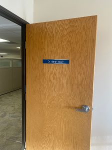 Open wooden door with name plate that says Dr. Sarah Story.