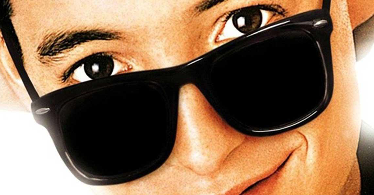 A close-up of the character Ferris Bueller, a young man peering out from over dark sunglasses.