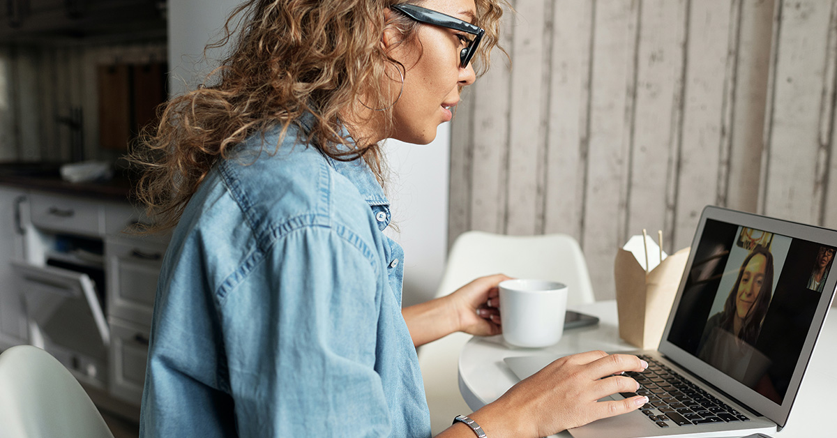 A woman working remotely participates in a video call on a laptop.