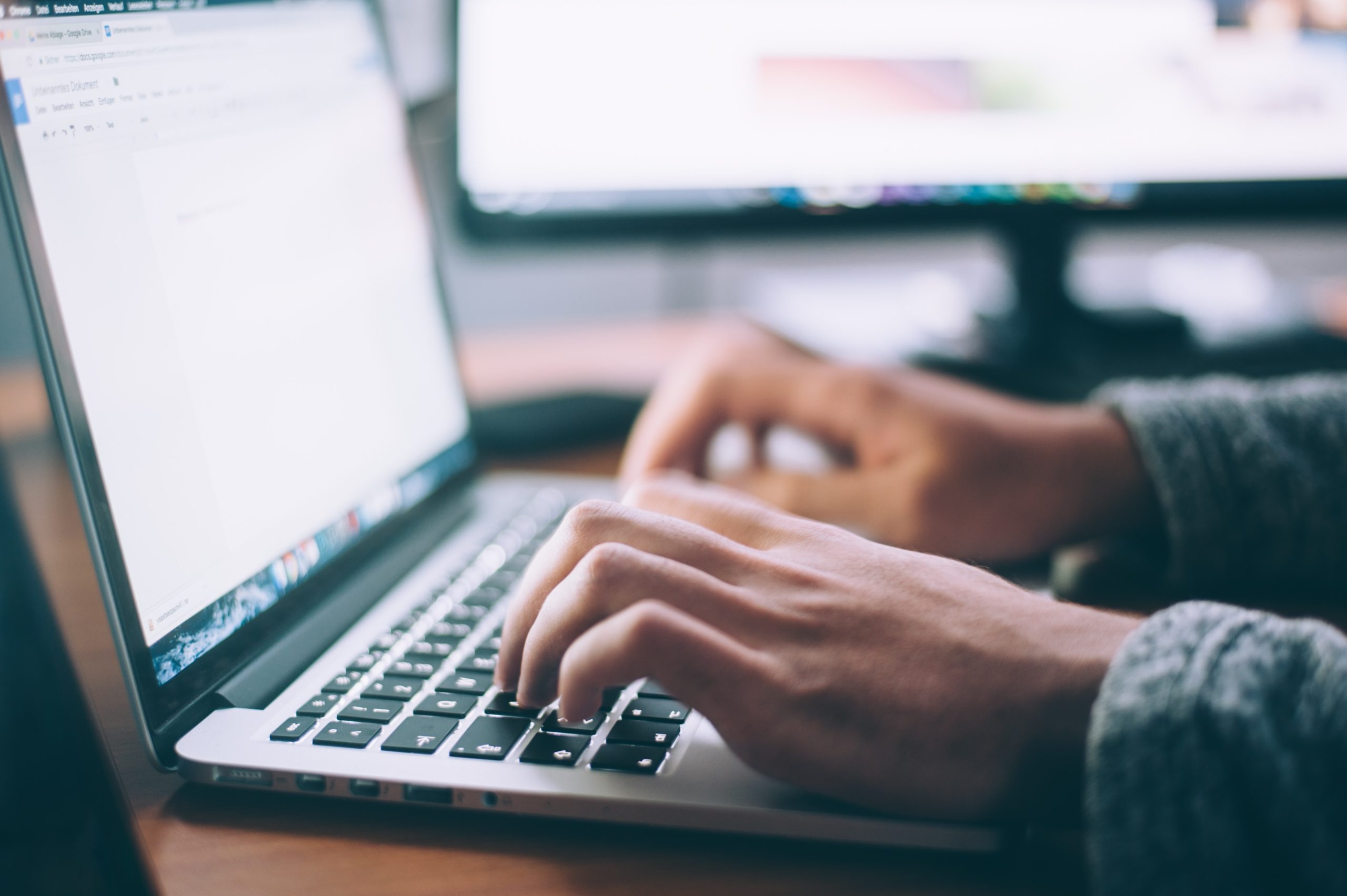 Hands typing on a laptop computer keyboard.