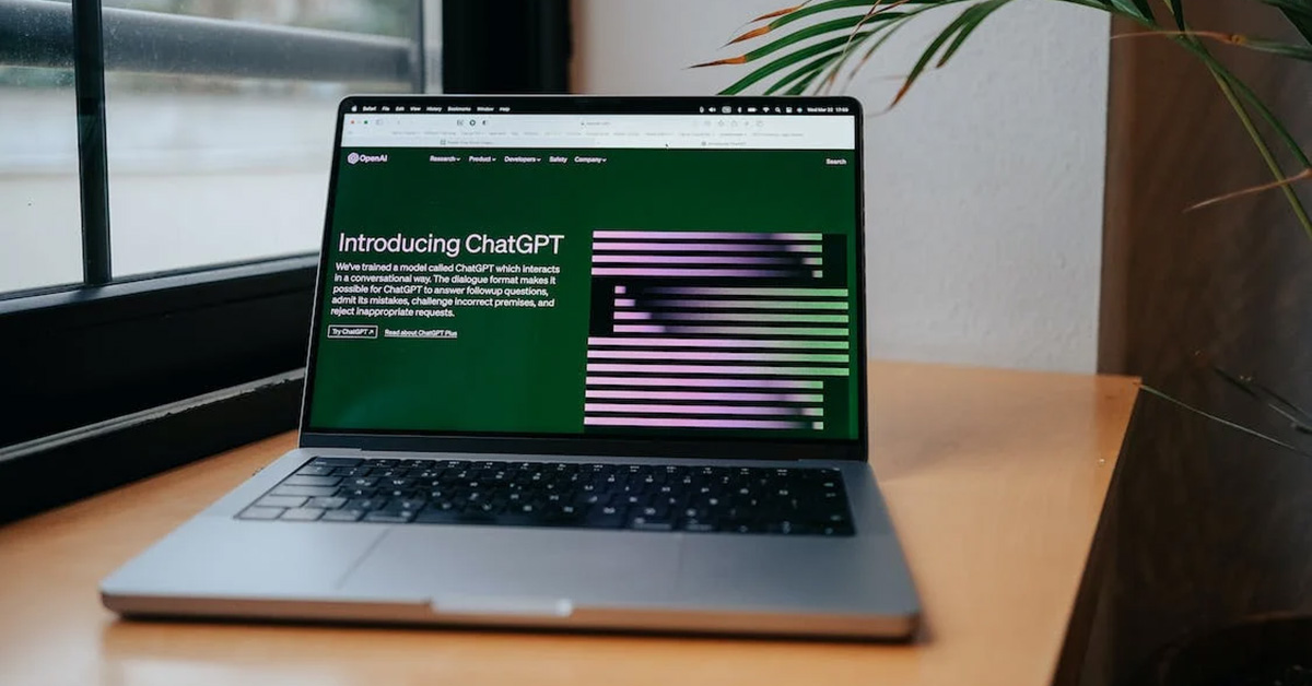 A laptop computer sits on a desk. On the screen is a webpage with the headline "Introducting ChatGPT."