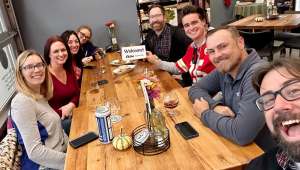 A group of people seated around a table take a selfie during a fall 2023 ELGL Supper Club.