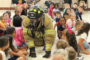 Firefighter crawling through school children for gear demonstration