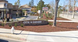 A shot of a shopping plaza on Seventeenth St in Santa Ana. There is landscaping and trees alongside wide sidewalks.