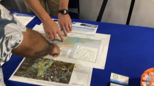 Two sets of hands pointing at different locations on a map at an outreach event