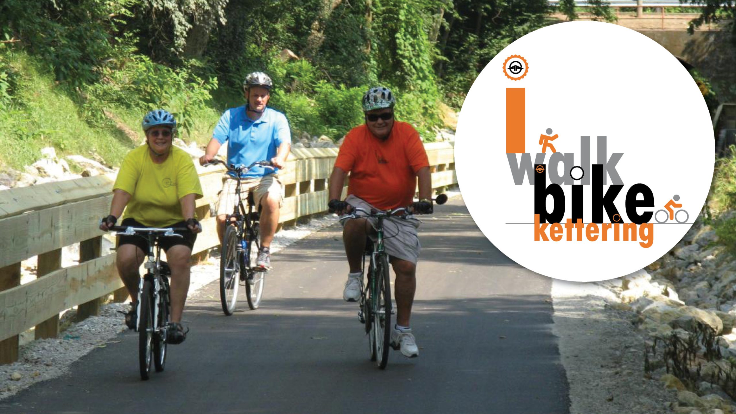 walk bike kettering web header 3 people riding bikes with helmets on bike path with walk bike kettering logo