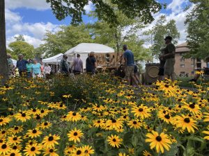 Yellow flowers are in the foreground with a crowd in the background.