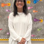 Woman with long dark hair and dark glasses wearing a white sweater