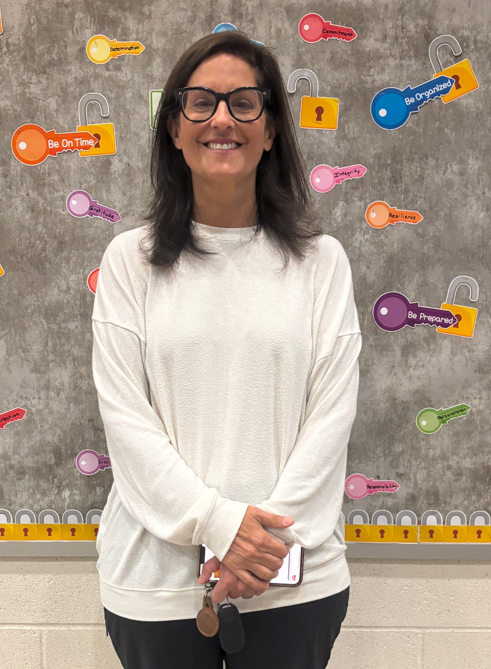 Woman with long dark hair and dark glasses wearing a white sweater