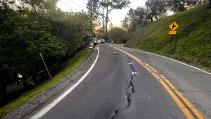 Bolinas Road in a rural area with a long crack running down the middle of it.