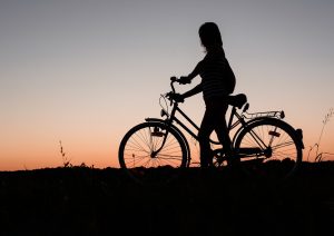 Silhouette of a woman on a bike watching the sunset.