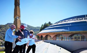 Workers on the Civic Center roof reviewing documents and plans