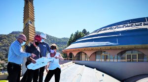 Workers on the Civic Center roof reviewing documents and plans