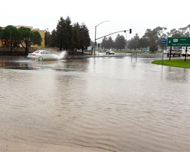 Car driving through flooded section of road.