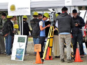 Student attending the Public Works Fair at the Civil Engineering booth, learning about how land surveying equipment is used.