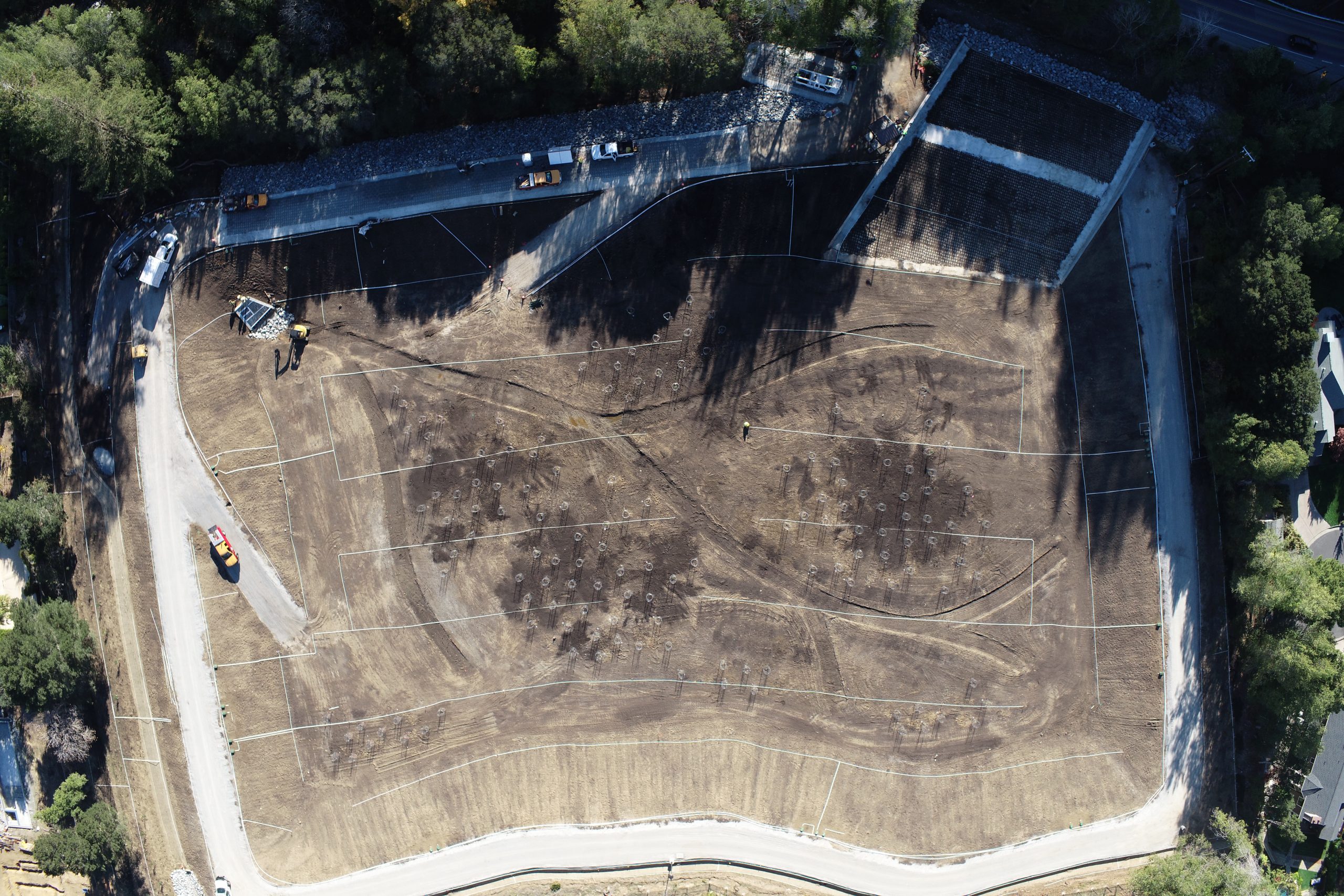 Aerial view of the current state of progress at the Sunnyside Flood Detention Basin Project, showing construction vehicles on a large area of dirt.