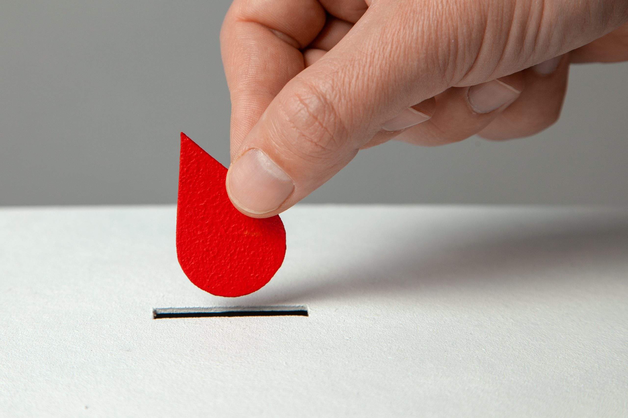 Blood donor. Man puts drop of blood in the piggy bank as donation. Concept donate blood save life