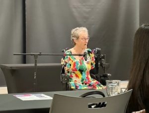 a woman in a powerchair sitting in front of a microphone