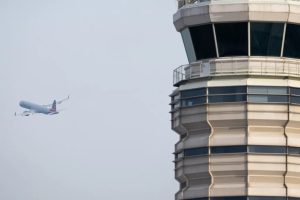 A plane flies away from an air traffic control tower