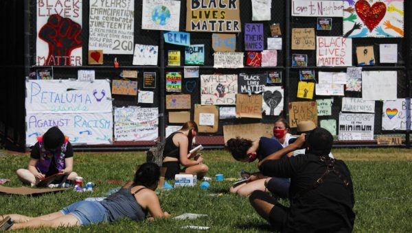 People standing in front of black lives matter signs on a wall