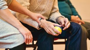 elderly man holding yellow and blue ball while woman gently touching mans wrist