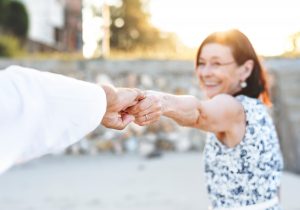 elderly couple holding extending to hold hands while woman is smiling looking towards to man