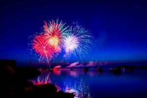 fireworks by the sea with a view of a few boats