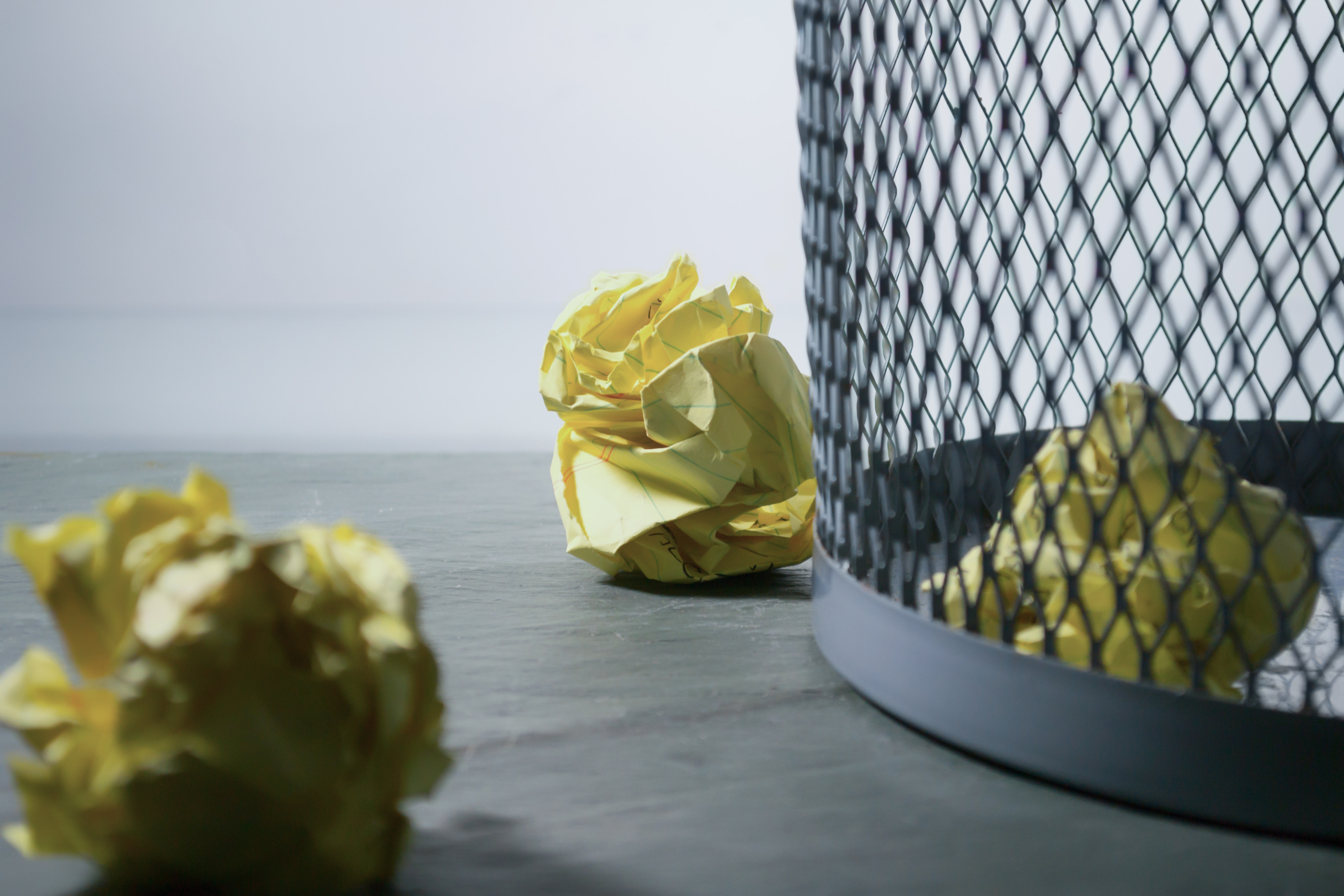 paper balls near trash with one paper ball inside the trashcan