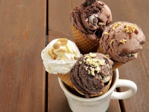 3 chocholate icecream cones, 1 vanilla ice cream cone inside a white mug