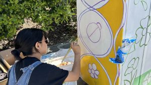 a person in overalls paints a utility box