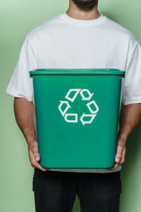 man holding green bin with recycling arrows