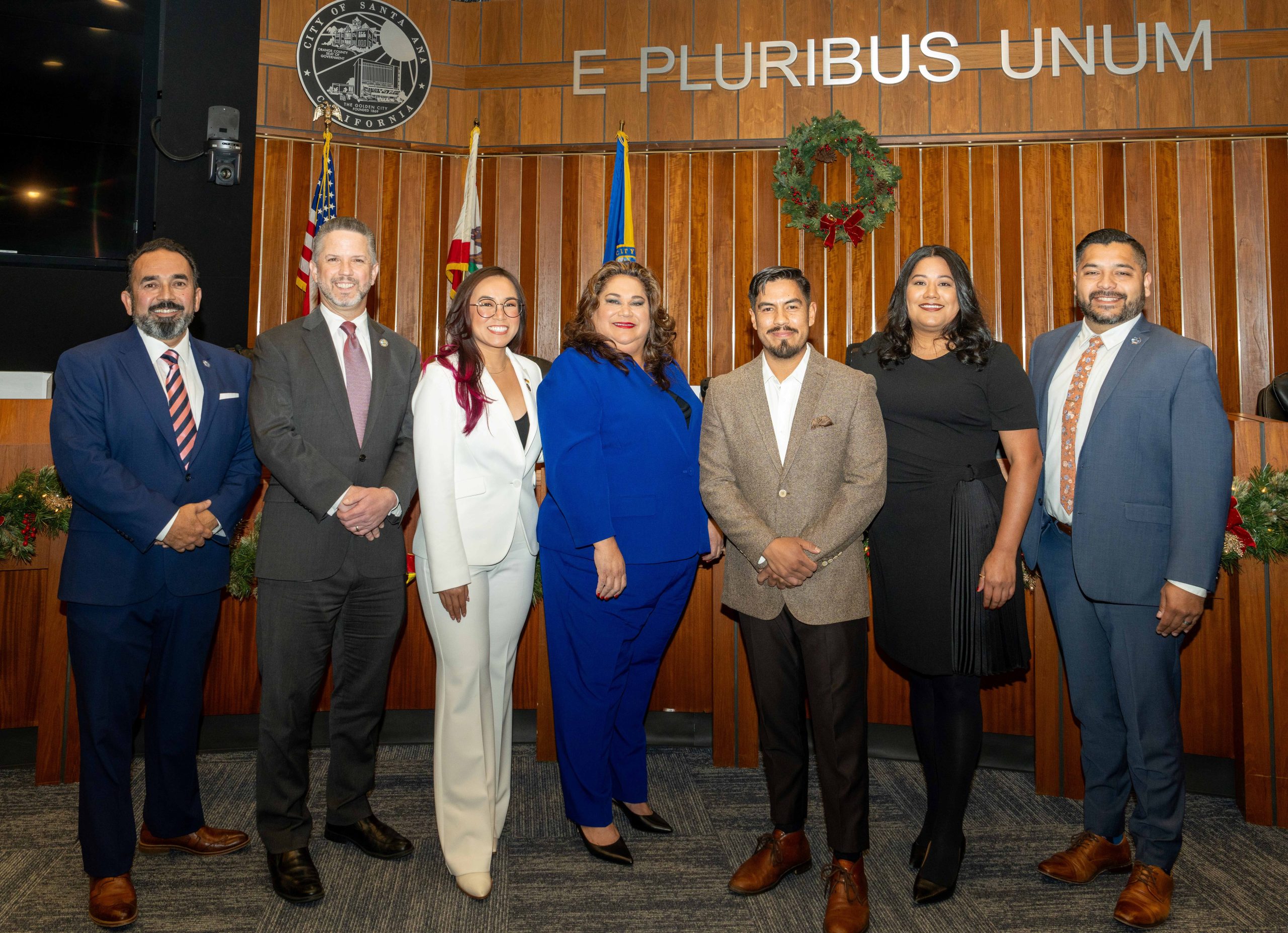 The Santa Ana City Council stands in front of a wooden dais.