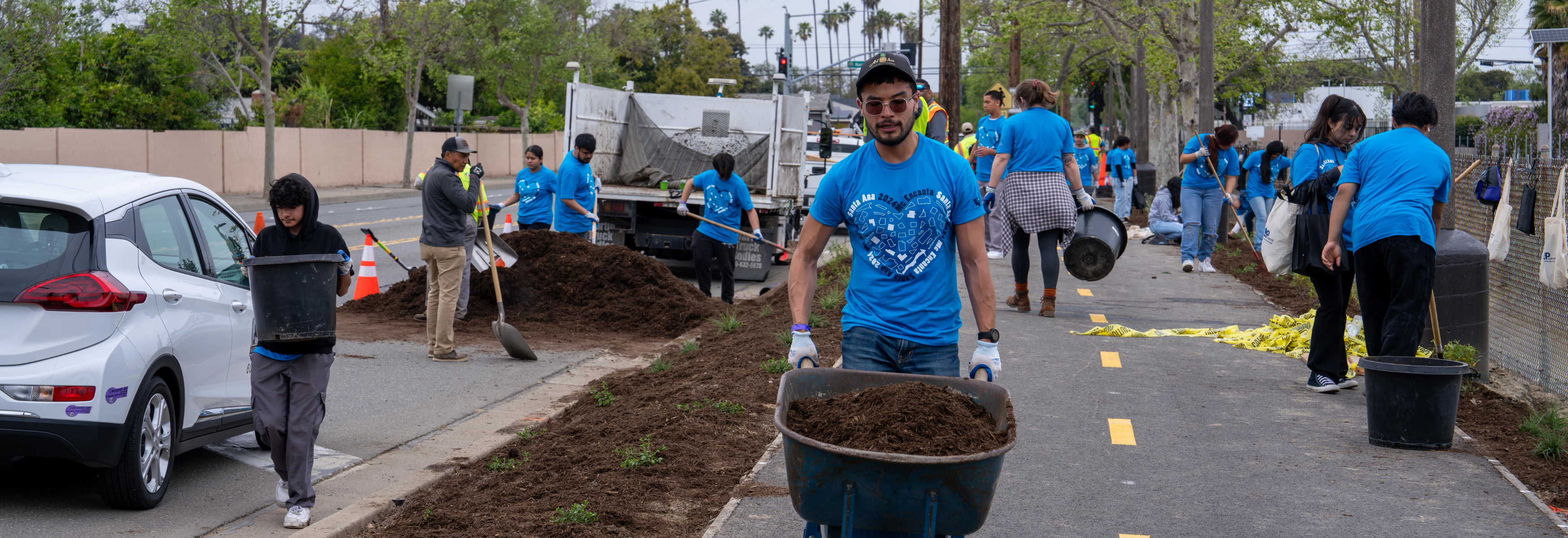 Community volunteer wheelbarrowing compost durinng the Me Encanta Santa Ana event