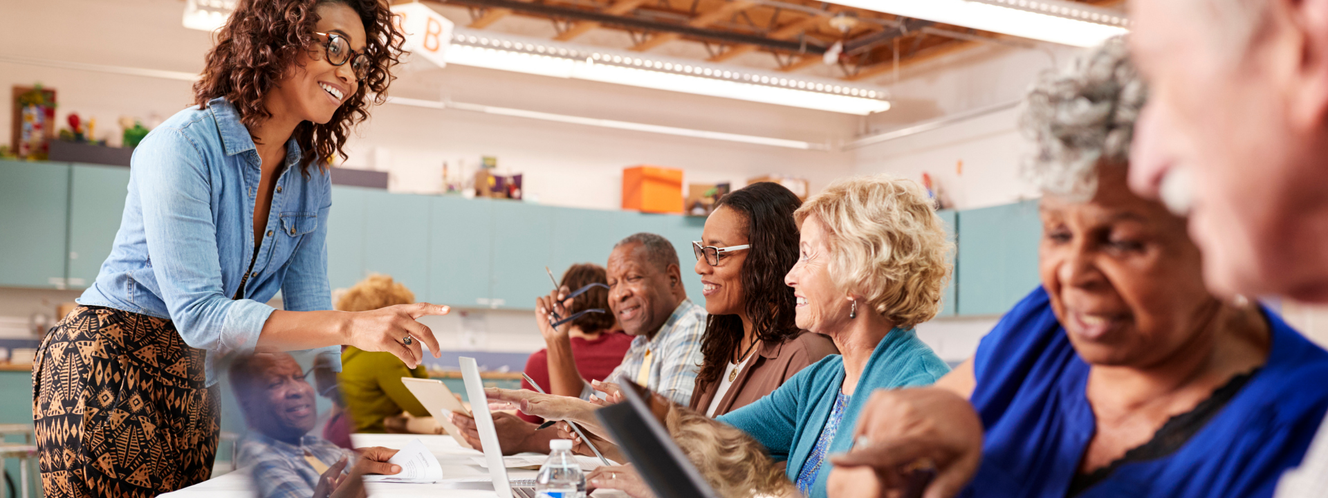 lady teaching seniors how to use a laptop