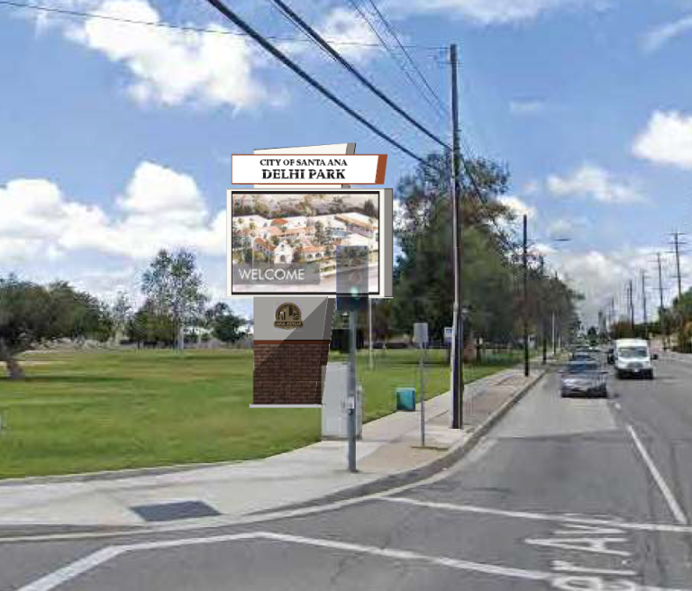 A digital marquee in a park next to a sidewalk and steet.