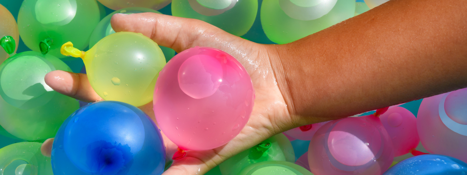 hand with three water balloons over a lot of them