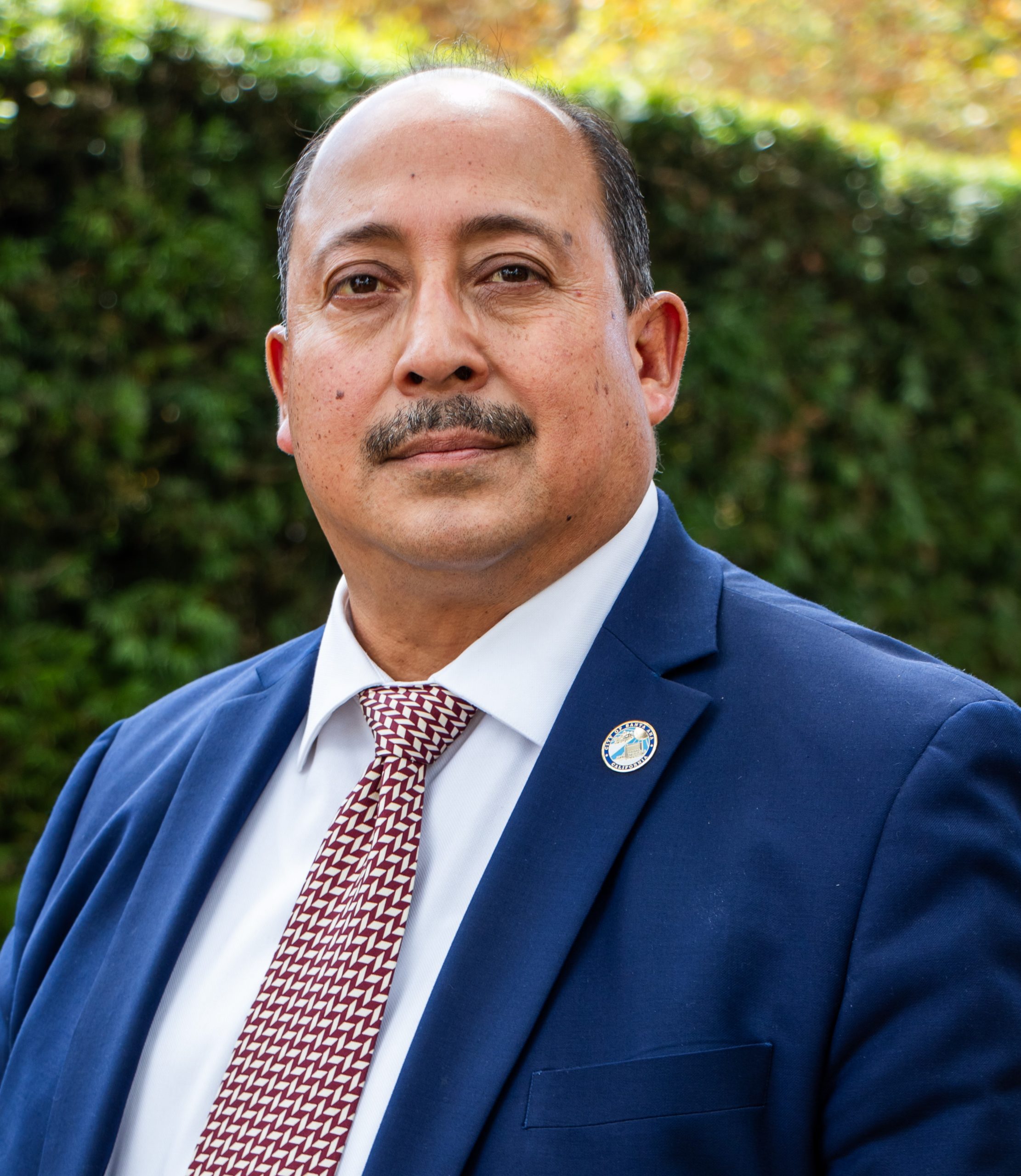 A man with a moustache wearing a suit and tie.