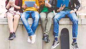 kids sitting on concrete using devices