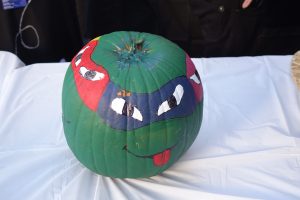 A pumpkin painted green with Teenage Mutant Ninja Turtles faces painted on