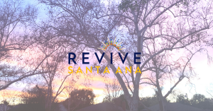 A faded image of sycamore trees at sunset overlaid with the words/logo, "Revive Santa Ana." At the bottom of the image there are roofs, and there are pink and orange clouds above them.