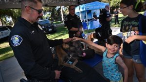 Police officer, dog, and children at an event at a park