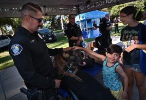 Police officer, dog, and children at an event at a park